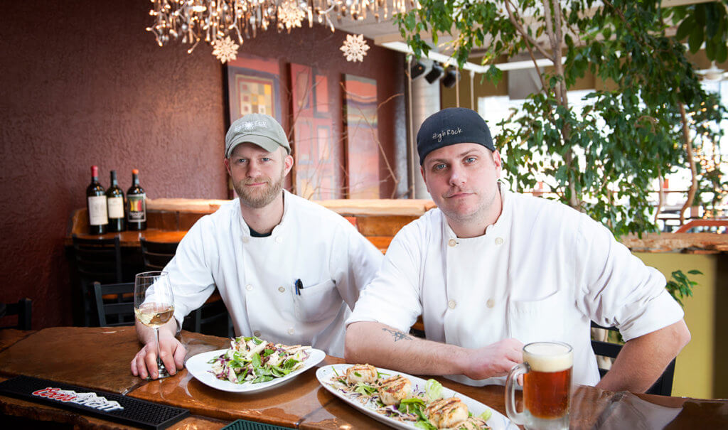 Chefs with food and drinks sitting at a bar