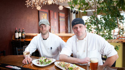 Chefs with food and drinks sitting at a bar